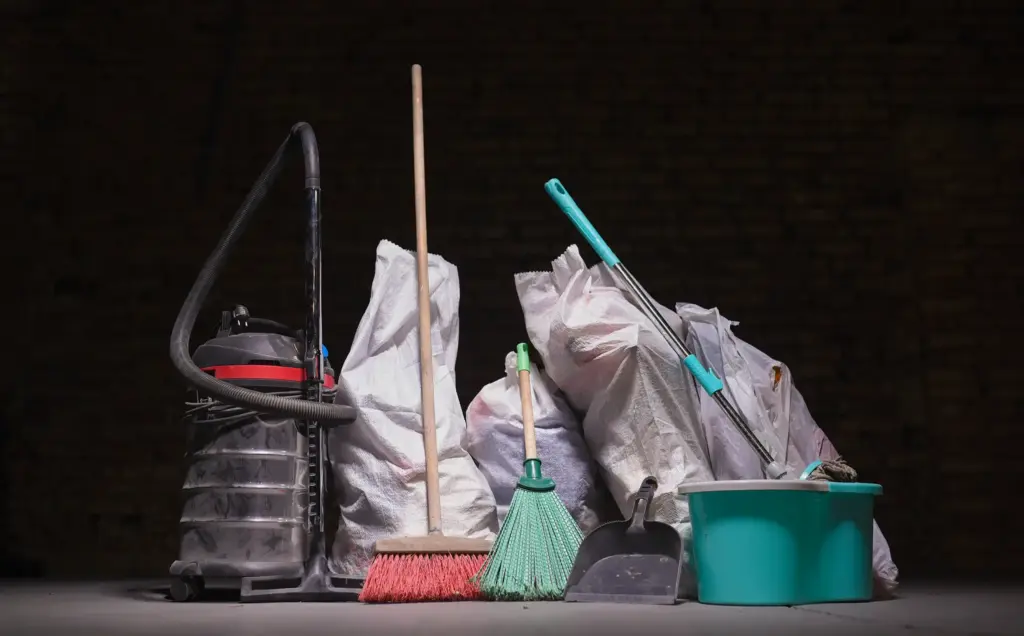 Reinigungsutensilien, Müllsäcke und Industriesauger in leerem Raum - Symbol für professionelle Entrümpelung und Räumungsservice